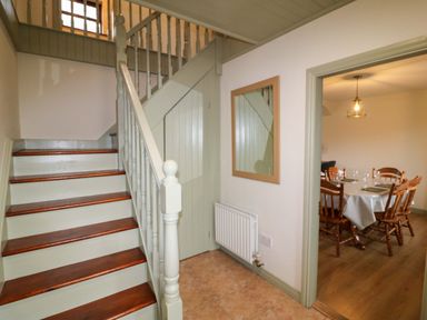 A hallway with stairs and a mirror at Shamrock House