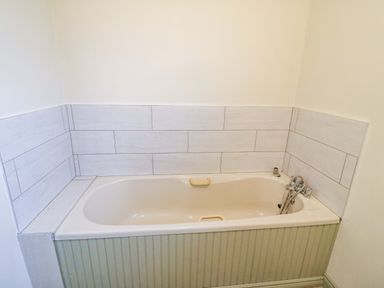 A bathroom with a bathtub and wall tiles at Shamrock House