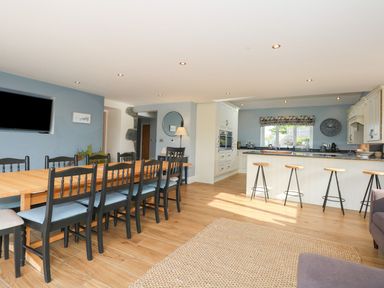 A kitchen with a dining table and bar stools at Criw in Bryncroes near Sarn Meyllteyrn