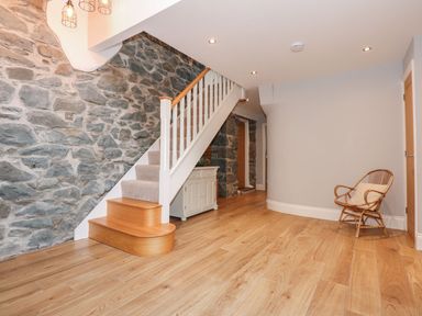A hallway with a staircase and a console table at Criw in Bryncroes near Sarn Meyllteyrn