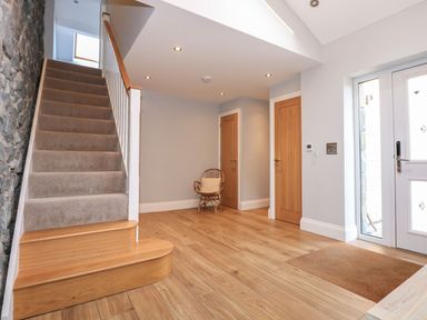 A hallway with stairs and a chair at Criw in Bryncroes near Sarn Meyllteyrn