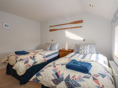 A bedroom with two beds and a bedside table at Criw in Bryncroes near Sarn Meyllteyrn