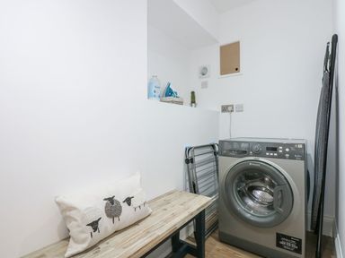 A laundry room with a washing machine and ironing board at Criw in Bryncroes near Sarn Meyllteyrn
