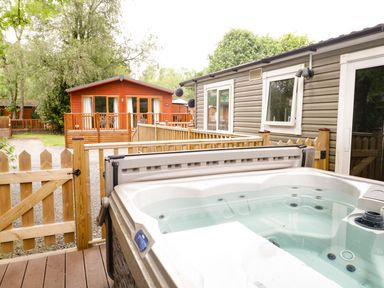 A hot tub with wooden cabins and a fence at Owls Nook Lodge Langdale 9, White Cross Bay near Windermere