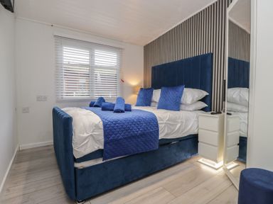 A bedroom with a bed and mirror at Owls Nook Lodge, Langdale 9, White Cross Bay near Windermere