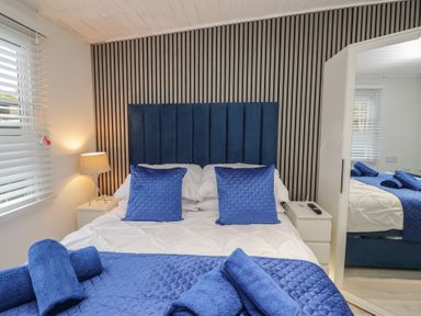 A bedroom with a bed and bedside table at Owls Nook Lodge, Langdale 9, White Cross Bay near Windermere