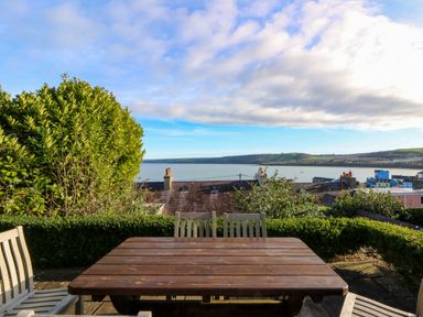 An outdoor seating area with a view over water at Zenobia, New Quay