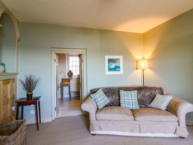 A living room with a sofa and lamp at Zenobia New Quay