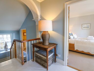 A hallway with a lamp and table at Zenobia in New Quay