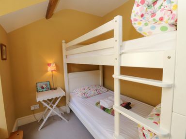 A bedroom with a bunk bed and side table at Zenobia in New Quay