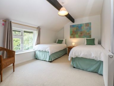 A bedroom with two single beds and a window at Neuadd Wen in Gaerwen