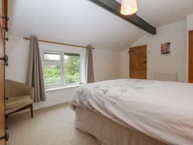 A bedroom with a bed, window, chair and door at Neuadd Wen in Gaerwen