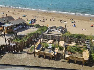 A beach scene with sun umbrellas and seating at Awel Deg in Cardigan