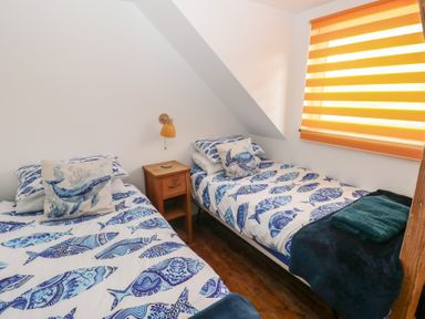 A bedroom with two beds and a nightstand at Awel Deg, Tresaith