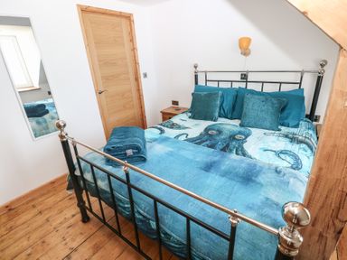 A bedroom with a bed and wooden furniture at Awel Deg, Tresaith
