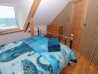 A bedroom with bed and dresser at Awel Deg, Tresaith