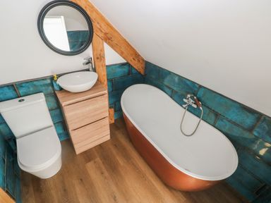 A bathroom with a bathtub, toilet, and sink at Awel Deg, Tresaith