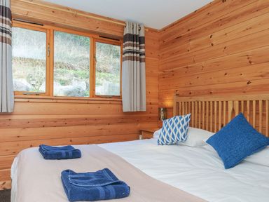 A bedroom with a bed, pillows, towels, and windows at Trevano in St Breward