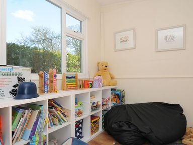 A playroom with a shelf of books and toys at Trevano in St Breward