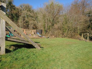 A playground with slides and swings in an outdoor play area at Pencarrow in St Breward