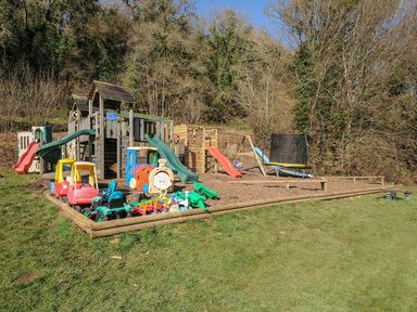 An outdoor play area with a playground equipment and toys at Trebah in St Breward
