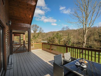 A deck with a table and chairs overlooking trees at Heligan in St Breward