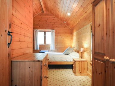 A bedroom with a bed and wooden furniture at Heligan in St Breward