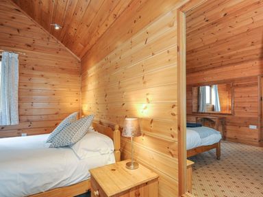 A bedroom with two beds and wooden walls at Heligan in St Breward