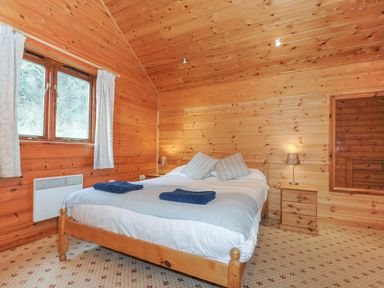 A bedroom with wooden walls and a large bed at Heligan in St Breward