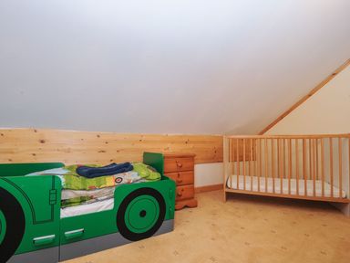 A children's bedroom with a car-shaped bed and a crib at Heligan St Breward
