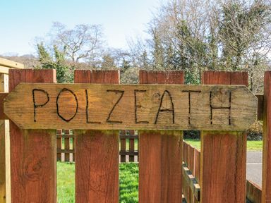 A wooden sign reading Polzeath near a fence at Polzeath in St Breward