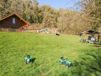 A garden with a house and playground equipment at Polzeath in St Breward