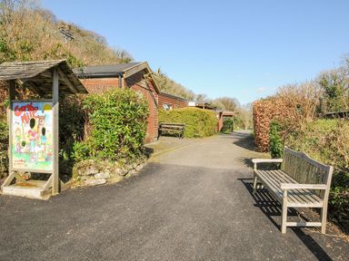 An outdoor pathway with a bench and sign at Coombe Mill in St Breward