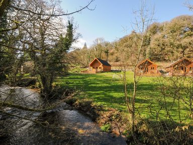 Wooden cabins and a stream in a grassy area at Polzeath in St Breward