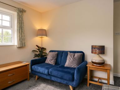 A living room with a blue sofa and a lamp at Buckbarrow in Seascale