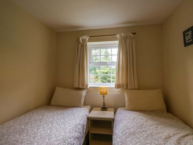 A bedroom with two beds and a lamp on the nightstand at Buckbarrow Seascale