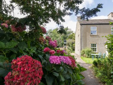 A garden with flowers and a table at Buckbarrow in Seascale