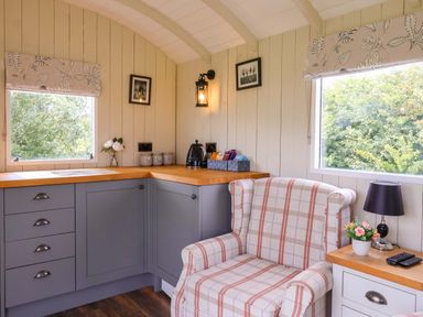 A kitchen with cabinets and a chair at Shepherds hut 