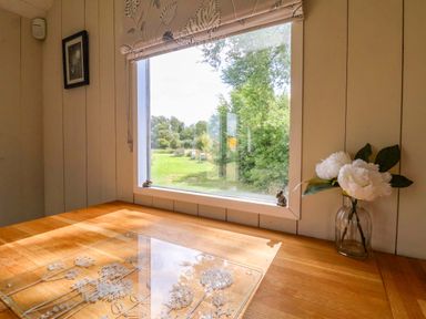 A table with a flower vase and window view at Shepherds hut