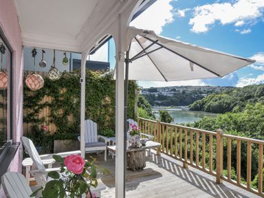 A deck with chairs and a table overlooking a river at Mayhurst in Looe