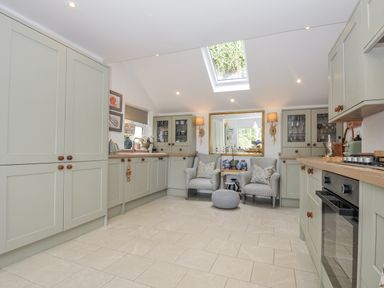 A kitchen with cabinets and seating area at Mayhurst in Looe