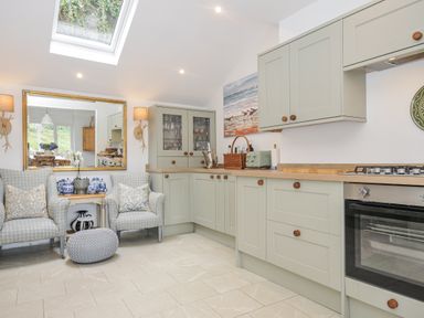 A kitchen with cabinets, oven, and seating area at Mayhurst in Looe
