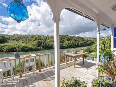 An outdoor area with table and chairs overlooking a river at Mayhurst in Looe