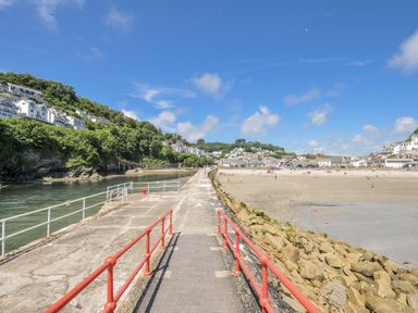 A pier leading to a beach with houses in the background at Mayhurst in Looe