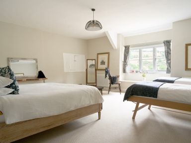 A bedroom with two beds and a chair at Holwell Farmhouse in Bampton