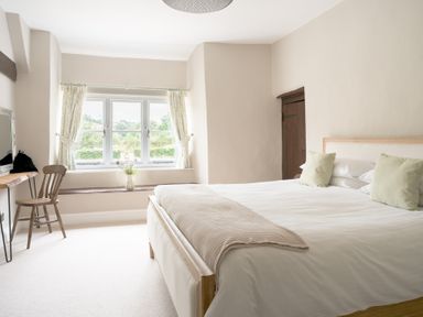 A bedroom with a bed and a chair at Holwell Farmhouse in Bampton