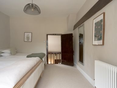 A bedroom with two beds and a door leading to stairs at Holwell Farmhouse in Bampton