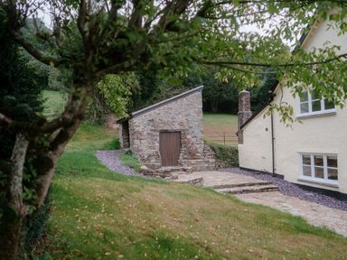 A stone building and patio area at Holwell Farmhouse in Bampton