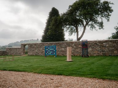 A garden with a stone wall and games at Holwell Farmhouse in Bampton