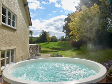 A hot tub with water outside a house at Holwell Farmhouse in Bampton